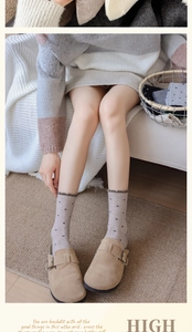 Close-up of thick wool crew socks with heart patterns and ruffled cuffs in warm brown tones