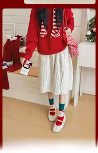 Cozy Christmas outfit with red knit sweater, festive patterned socks, and white pleated skirt
