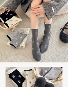 Detail of floral knit socks with delicate ruffle cuffs and small flower embroidery patterns