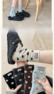 Close-up of thick polka dot socks with 'nice' labels paired with gray felt clogs