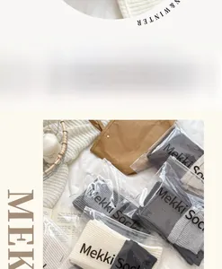 Detail of color-block knit leg warmers in various gray tones with branded zipper packaging