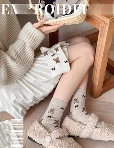 Close-up of cozy beige mid-calf socks with cute brown bear and bow embroidery