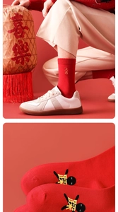 Close-up of red New Year socks with golden embroidery and graphic sole detail