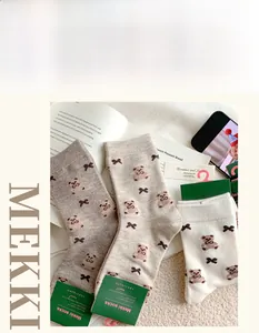 Three pairs of autumn winter knit socks with bear and bow patterns in warm neutral colors