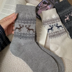 Thick wool socks for women with vintage Fair Isle reindeer pattern in winter home setting