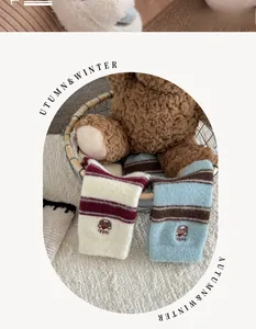 Gros plan de chaussettes d'hiver épaisses avec broderie ours et texture velours rayée