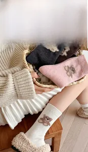 Detail of wool mid-calf socks with cute knitted bear pattern in assorted warm colors