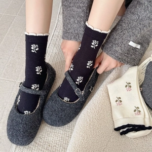 Floral cashmere socks with wavy cuffs paired with vintage Mary Jane shoes on cozy rug