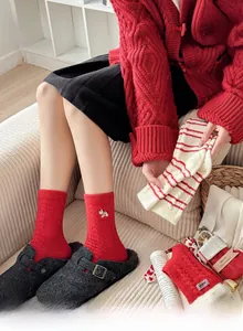 Detailed view of red Christmas socks with cute white rabbit embroidery and warm striped patterns