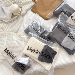 Gray patchwork rib-knit leg warmers in branded packaging on a cozy minimalist background