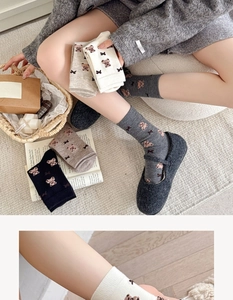 Close-up of cute bear and bow jacquard pattern on warm knit crew socks in neutral tones