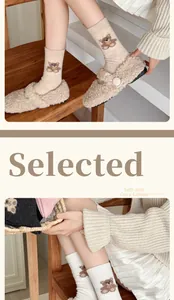 Detail of soft oat-colored wool socks featuring cute bear embroidery and ribbed texture
