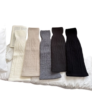 Set of five knitted leg warmers in neutral colors with cable textures for winter