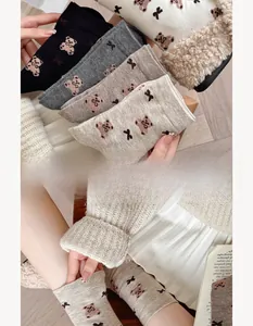 Close-up of cozy wool socks with bear pattern and fluffy plush cuffs in warm earth tones