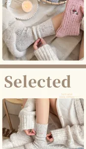 Detailed embroidery of a bird on warm, colorful flecked wool socks in a cozy setting