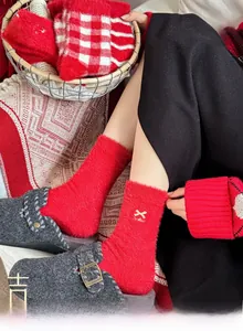 Détail de chaussettes festives en velours de vison rouge chaud avec broderie blanche