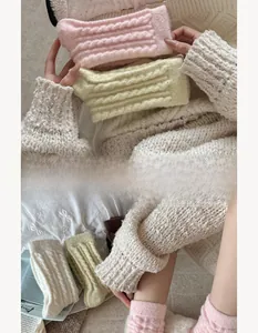 Detailed cable knit texture of macaron-colored warm leg warmers on white bedding