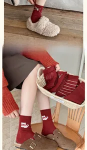Detailed close-up of dark red knit wool socks with cat embroidery and a white ribbon bow
