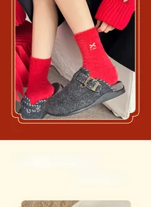 Détail de chaussettes en peluche rouge avec nœud doré et chaussons en feutre gris d'hiver