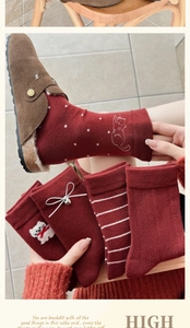 Detailed knit texture of red wool socks featuring polka dots and cute animal embroidery