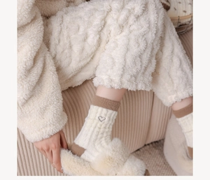 Gros plan de chaussettes d'hiver chaudes avec broderie cœur et tenue d'intérieur