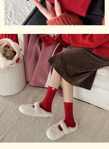 Détail de chaussettes en maille rouge avec étiquette fleurie et chaussons en peluche