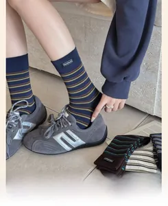 Close-up of retro striped cotton socks featuring a 'Handmade' fabric label at the cuff