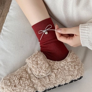 Thick warm dark red wool socks with bow tie and heart charm paired with plush beige slippers