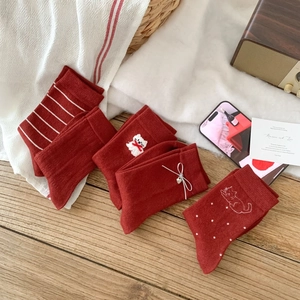 Five pairs of warm dark red wool socks with diverse patterns on wooden floor