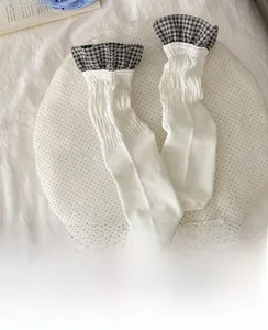 Detail of white cotton crew socks featuring pleated texture and black check lace trim