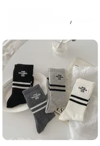 Close-up of four colors of striped cotton socks with letter embroidery on white plate