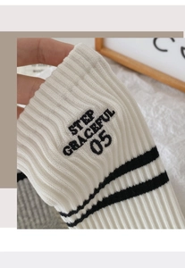 Macro shot of white ribbed knit fabric with black Step Graceful 05 embroidery and stripes