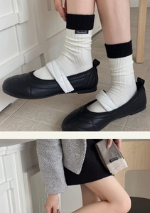 Close-up of contrast color knit socks with handmade label and quilted Mary Jane shoes