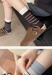 Detailansicht gestreifter Wollsocken kombiniert mit gemütlichen Plüsch-Clogs im Haus