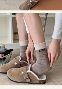 Close-up of cozy knitted socks with handmade label and warm suede mule slippers