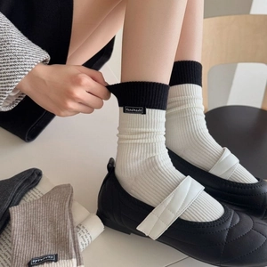 Casual color-block crew socks with handmade label worn with quilted Mary Jane shoes