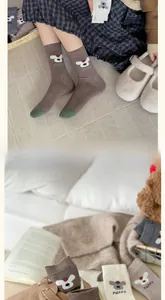 Dettaglio di calze di lana con ricamo di cane e scritta PUPPY in toni caldi