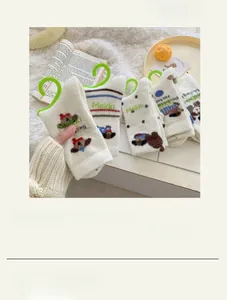 Detail von drei Paar weißen Thermo-Plüschsocken mit grünem Welpen-Stick und Spitzenbesatz