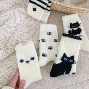 Lot de cinq paires de chaussettes thermiques chat en maille pelucheuse beige sur tapis