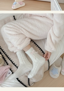 Detail of plush off-white mink velvet socks with pink ribbon bows for winter comfort