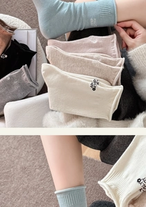 Detail von bestickten Wollsocken mit Fully Enjoy Text in verschiedenen Pastellfarben