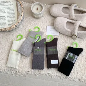Five pairs of warm knitted wool crew socks in assorted autumn colors on plush background