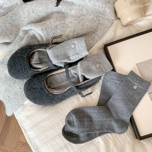 Dark grey Mary Jane wool shoes paired with knitted crew socks featuring metal buckle accents