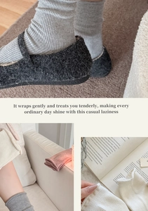 Detailed view of grey wool loafers paired with ruffled crew socks in a cozy home setting