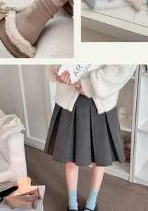 Details von warmem grauem Wollrock, weißem Strick-Cardigan und blauen Socken