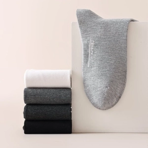 Five pairs of men's cotton crew socks in neutral tones with minimalist branding