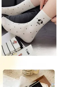 Detail of cream cotton crew socks featuring black polka dots and a cute puppy pattern