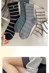 Detail of striped cotton socks featuring a silver 'Smile' metal badge on the ankle cuff