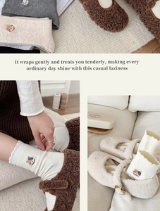Detailed close-up of cat embroidery on warm ribbed knit wool-blend socks and plush slippers