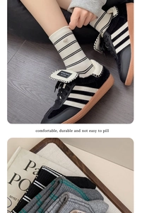 Detail of striped knitted crew socks with metal smile buckle and ribbed texture